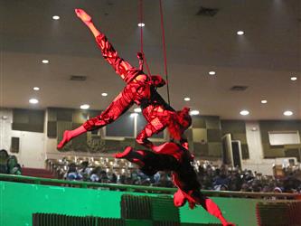 Two dancers hang in mid-air above the student audience